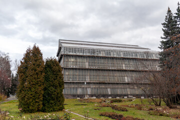 Fototapeta na wymiar Tall glass building botanical garden in the city of Tomsk, Russia. There are many exotic plants inside the building.
