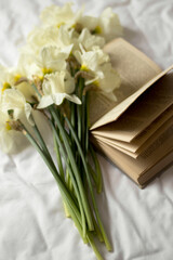 flowers on the bed with a favorite book. The best morning with your favorite book and a bouquet of flowers. Morning freshness.