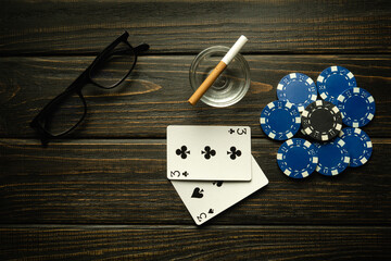 Playing poker with a winning combination of one pair. Cards with chips and glasses with a cigarette on a black vintage table in a poker club