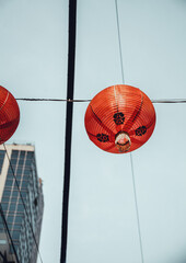 Close up shot from below of a red chinese lantern hanging from an electriticy wire in the heart od...