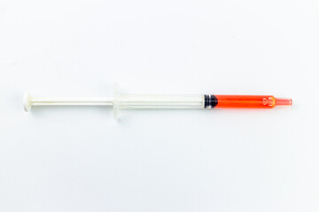 Fototapeta premium Red plastic syringe on a white background. Isolated on white.