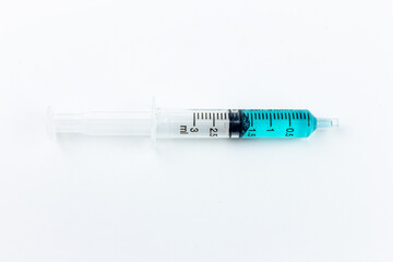 syringe with blue liquid inside on a white background. close-up of a syringe