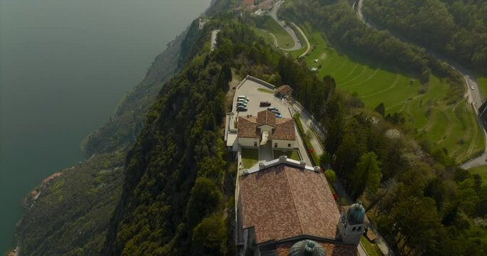 Cinematic aerial dolly of scenic hilltop village comune and Sanctuary of Montecastello overlooking Lake Garda and forest trails. Tignale, Italy.