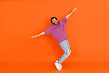 Fototapeta na wymiar Positive indian guy fooling on orange studio background