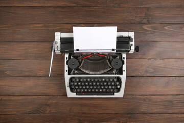 vintage typewriter on the table with blank paper on wooden desk - concept for writing, journalism, blogging