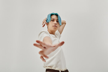 Asian young dancer with blue hair exercising on white background
