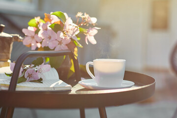 Cup of coffee flowers and notebook on the small black table