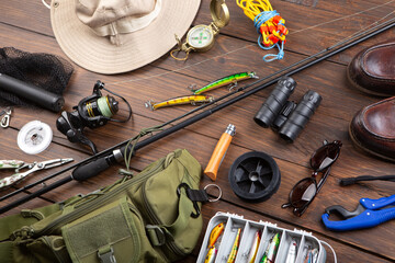 Fishing rod, tackles and other stuff for recreation activity on the wooden desk. Fishing season concept