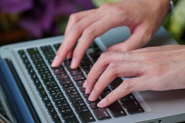 A young woman is typing a laptop.