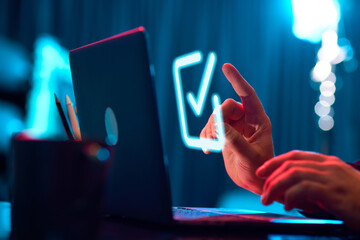 Businessman touching virtual, neon colored, digital icon of checkmark. Finishing tasks. Development...