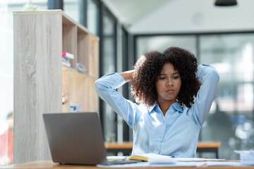 Young American businesswoman working on the laptop with documents and stressing at work from working on financial documents in office Overworked woman concept.
