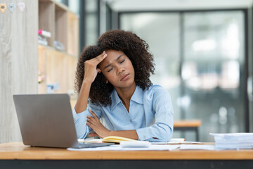 Young American businesswoman working on the laptop with documents and stressing at work from working on financial documents in office Overworked woman concept.