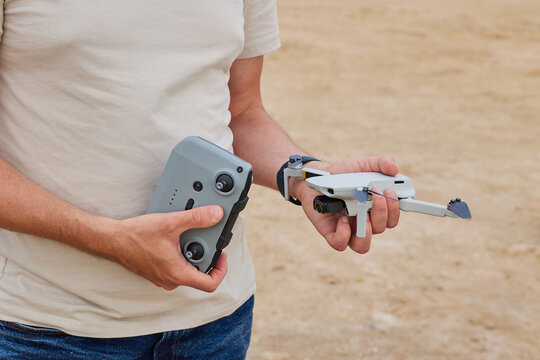 A man holds a drone and a remote control for a drone in his hands