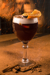 Alcoholic cocktail of beer, champagne and liqueur with orange and anise in a glass with fire and sparks.