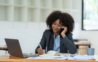 Obraz premium Young african american businesswoman sitting at the table in the office while making with a business colleague in receiving good news on modern business contracts.