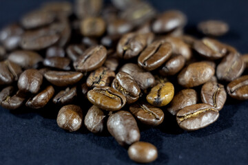 Close up on a bunch of roasted coffee beans, light brown and yellow roast. These are Arabica coffee beans, with no background, shiny.