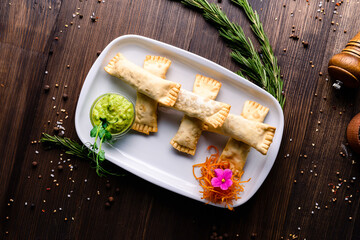 Minced meat in dough with guacamole and carrots, pasties in plate. - obrazy, fototapety, plakaty