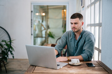 Fototapeta premium A Handsome young man sitting on laptop reading online news. freelance concept.