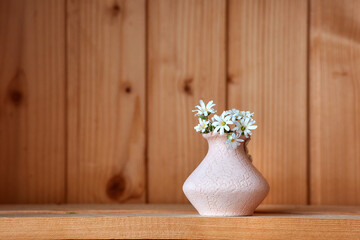 One vase with flowers at wooden background from side view - Powered by Adobe