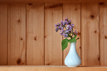 One vase with flowers at wooden background from side view