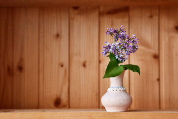 One vase with flowers at wooden background from side view