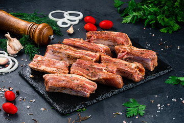 Portion pork ribs for barbecue with onion, tomatoes, sauce and spices.