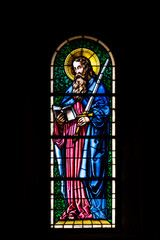 Stained glass inside a Christian church in Europe depicting Church Saint figure. Close up shot, no people, low key