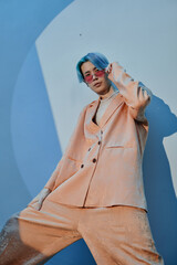 Vertical image of Asian man in stylish suit looking at camera against blue background