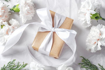 Fototapeta na wymiar Gift box with white bow and flowers on crumpled paper background