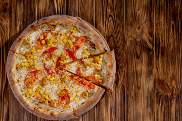 Pizza for children on a cream base with chicken fillet, tomatoes, corn and mozzarella cheese on wood background. Copy space.