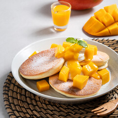 Delicious Japanese souffle pancake with dice mango and jam on gray table background.