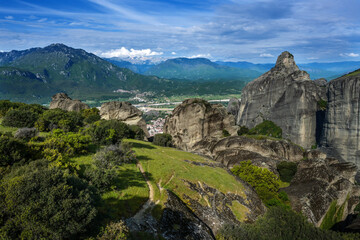 Fototapeta na wymiar View from the Meteora rocks over the village Kalambaka in the valley to the mountains and snow-capped peaks, landscape in central Greece, cloudy blue sky, copy space, selected focus