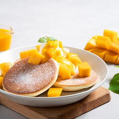 Delicious Japanese souffle pancake with dice mango and jam on gray table background.