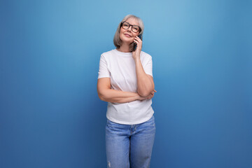 gray-haired mature woman studying digital technology smartphone on a bright studio background