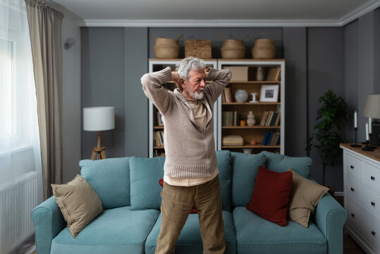 Sporty elderly guy practicing yoga indoors. Senior man doing stretching exercise at home. Active lifestyle and healthcare in any age. Old retired person light fitness training in living room