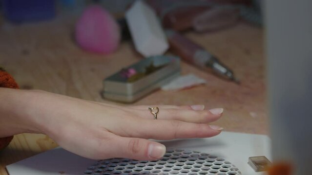 Anonymous manicurist using nail buffing block to polish girl's hands, slow motion