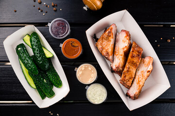 Fried pork fillet steak with salted cucumbers and sauces in a paper box.