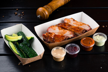 Dinner fried pork fillet steak with salted cucumbers and sauces in a paper box.