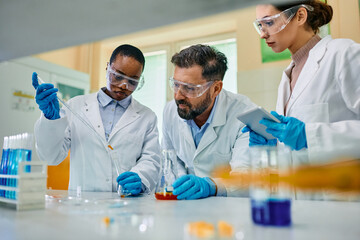 Multiracial team of pharmaceutical chemists working on scientific research together in laboratory.