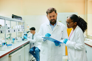 Two scientists cooperating while analyzing research data in laboratory.