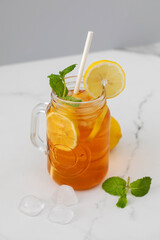 A glass with a summer cooling drink. Iced tea with lemon and mint.