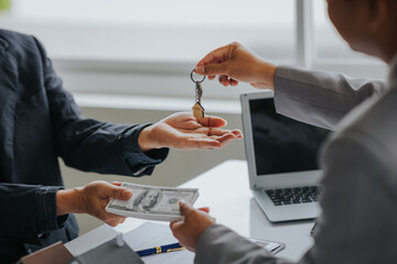 Male businessman or real estate agent holding house key for his client after signing contract in...