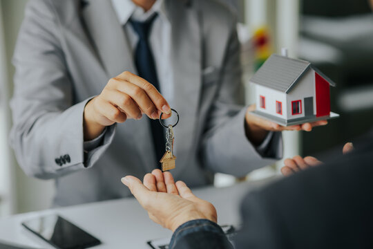 Male businessman or real estate agent holding house key for his client after signing contract in office concept for real estate Moving house or renting property