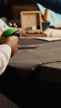 Vertical video Student and old tailor cutting material for handcraft in atelier, beginner using scissors to cut fabric before sewing and designing clothes. Couturier and apprentice. Handheld shot