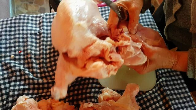 Cutting chicken meat. A female person cuts an organically raised chicken with a sharp knife	