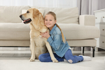 Cute child hugging her Labrador Retriever on floor at home. Adorable pet