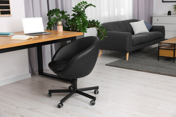 Stylish room interior with comfortable office chair, desk and houseplant
