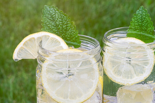 mason jars filled with fresh lemonade and a sprig of lemon balm mint