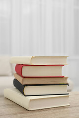 Stack of hardcover books on wooden table indoors