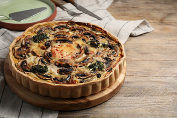 Delicious quiche with mushrooms on wooden table, space for text